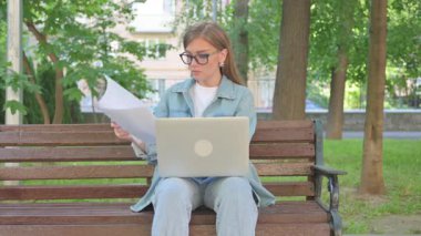 Dışarıda Otururken Dizüstü bilgisayarla Belgeleri İnceleyen Kadın