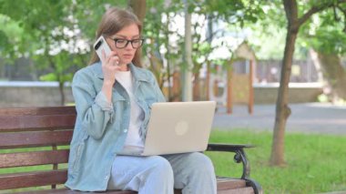 Laptop kullanırken Telefonda Konuşan Genç Kadın