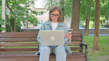 Açık havada otururken Akıllı Telefon ve Laptop Kullanan Kadın