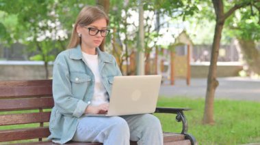 Park Bench 'te dizüstü bilgisayarı olan Ciddi Genç Kadın