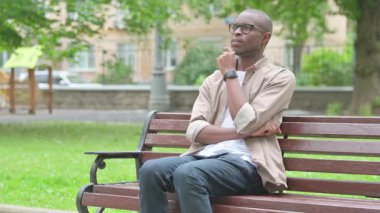 Genç Afrikalı bir adam Park Benç 'inde Düşünüyor