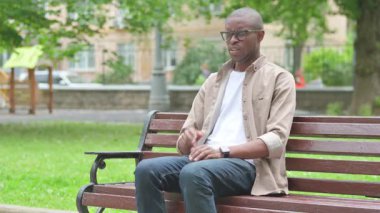 Park Benç 'inde öksüren hasta Afrikalı genç adam.