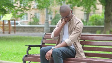 Genç Afrikalı bir adam Park Bench 'inde boynuna masaj yapıyor.