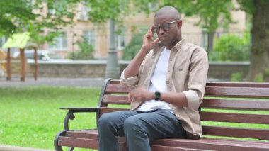 Genç Afrikalı bir adam parkta baş ağrısı çekiyor.