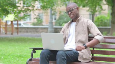 Park 'ta dizüstü bilgisayar kullanan Sırt Ağrısı Olan Genç Afrikalı Adam
