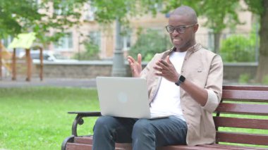 Genç Afrikalı Adam Park 'taki laptopta video görüşmesi yapıyor.