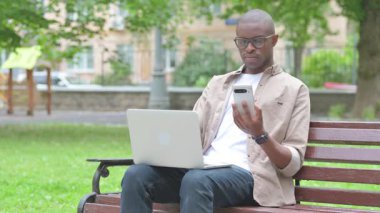 Akıllı telefon ve dizüstü bilgisayar kullanan genç bir Afrikalı.