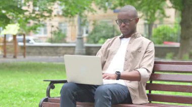 Park Bench 'te dizüstü bilgisayarı olan ciddi bir Afrikalı.