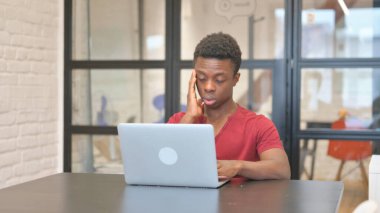 Genç Afrikalı Adam dizüstü bilgisayarda yazarken baş ağrısı çekiyor