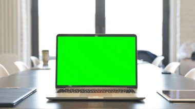 Laptop with Green Screen on Desk in Office