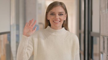 Merhaba demek için el sallayan genç kadının portresi.
