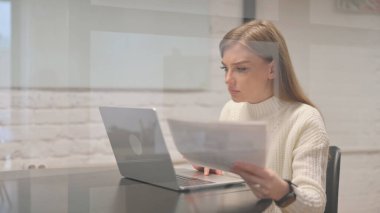 Belgeler ve Laptop üzerinde çalışan Kadın Çalışan