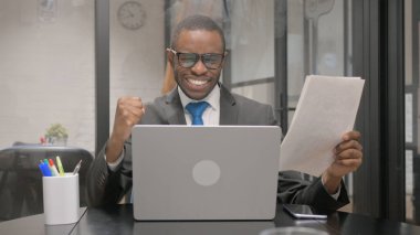 Belgeler ve Laptop Üzerinde Çalışan Afrikalı İş Adamı Heyecanlı