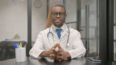 Kameraya bakan gülümseyen erkek doktorun portresi.