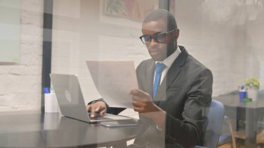 Afrika işadamı belgeleri ve Laptop üzerinde çalışma