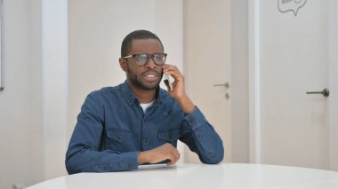 Genç Afrikalı adam müşteriyle telefonda konuşuyor.
