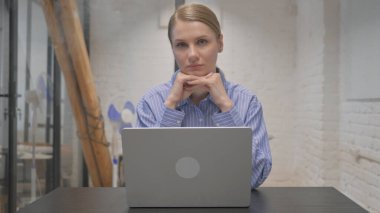 Ofiste kameraya bakan genç bir kadın.