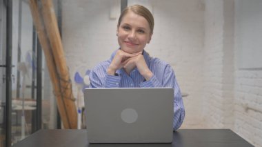 Gülümseyen Genç Kadın Çalışma Alanında Kameraya Bakıyor