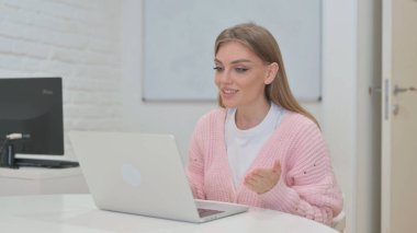 Dizüstü bilgisayarla video sohbeti yapan yaratıcı genç kadın.