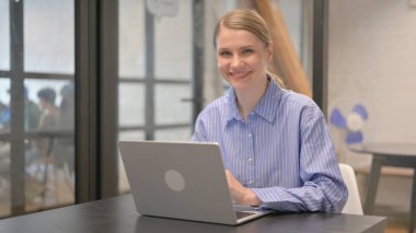 Gülümseyen Genç Kadın Çalışma Alanında Kameraya Bakıyor