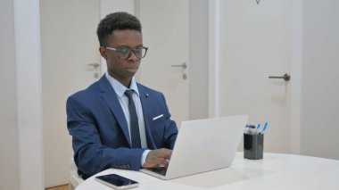 Masada çalışan gülümseyen Afrikalı genç iş adamı