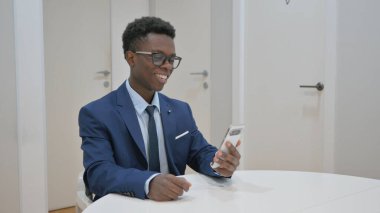 Gülümseyen Afrikalı İş Adamı Video Görüşmesi İçin Akıllı Telefon Kullanıyor