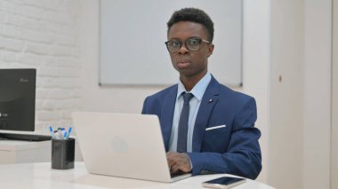 Bilgisayarda çalışırken Kameraya Odaklanan İşadamı