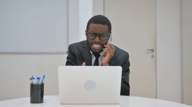 Sıkıntılı bir Afrikalı Amerikalı işadamı yoğun bir telefon görüşmesi yaptı. Dizüstü bilgisayarında çalışırken hayal kırıklığını dile getirdi.