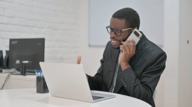 Sıkıntılı bir Afrikalı Amerikalı işadamı yoğun bir telefon görüşmesi yaptı. Dizüstü bilgisayarında çalışırken hayal kırıklığını dile getirdi.