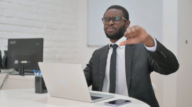 Onaylamayan Afro-Amerikan iş adamı ofis masasından olumlu bir jest yapıyor.