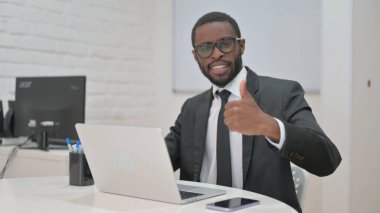 Hevesli Afrikalı Amerikalı iş adamı ofis masasından onay veriyor.