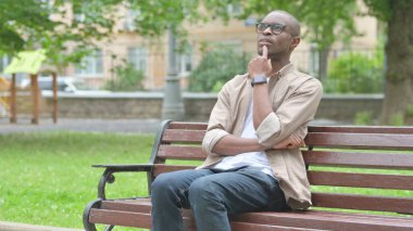Genç Afrikalı bir adam Park Benç 'inde Düşünüyor