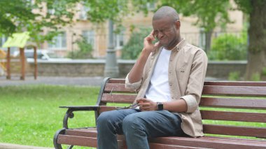 Genç Afrikalı bir adam parkta baş ağrısı çekiyor.