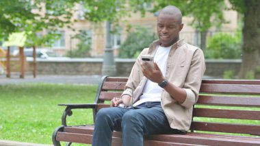 Akıllı telefonu ve etkileyici bir jesti olan genç bir Afrikalı.