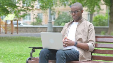 Genç Afrikalı Adam Park 'taki laptopta video görüşmesi yapıyor.