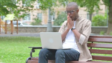 Park Bench 'te dizüstü bilgisayar kullanan kafası karışmış bir Afrikalı.