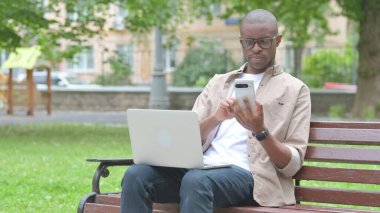 Akıllı telefon ve dizüstü bilgisayar kullanan genç bir Afrikalı.