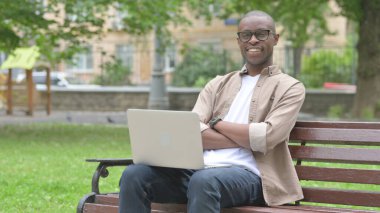 Genç Afrikalı Adam Park 'ta dizüstü bilgisayarla gülümsüyor