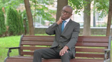 Parkta otururken Afrikalı İşadamı Boynuna Masaj Yapıyor