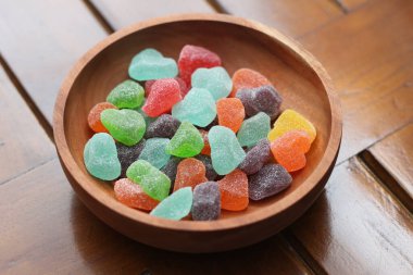 a close up of gummy candies of various colors and fruit flavors served in a wooden bowl.