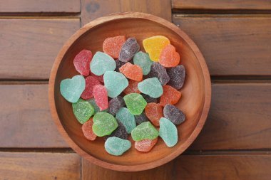 a close up of gummy candies of various colors and fruit flavors served in a wooden bowl.