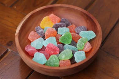 a close up of gummy candies of various colors and fruit flavors served in a wooden bowl.