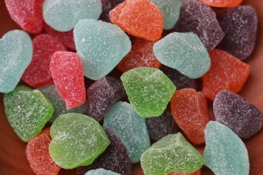 a close up of gummy candies of various colors and fruit flavors served in a wooden bowl.