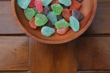 a close up of gummy candies of various colors and fruit flavors served in a wooden bowl.