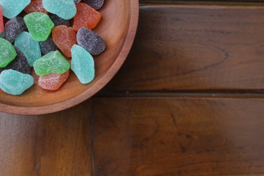 a close up of gummy candies of various colors and fruit flavors served in a wooden bowl.