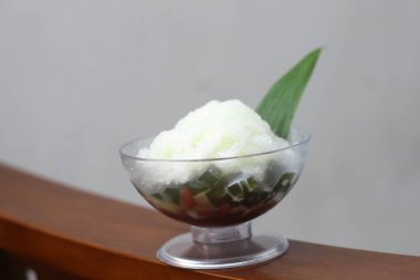 Es Kacang Merah or a cold drink made from red beans boiled with brown sugar served with coconut milk, shaved ice and covered with sweetened condensed milk chocolate and syrup. Indonesian traditional food photo concept.