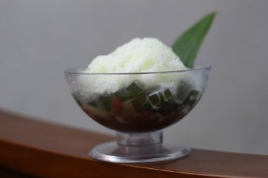 Es Kacang Merah or a cold drink made from red beans boiled with brown sugar served with coconut milk, shaved ice and covered with sweetened condensed milk chocolate and syrup. Indonesian traditional food photo concept.