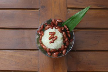 Es Kacang Merah or a cold drink made from red beans boiled with brown sugar served with coconut milk, shaved ice and covered with sweetened condensed milk chocolate and syrup. Indonesian traditional food photo concept.