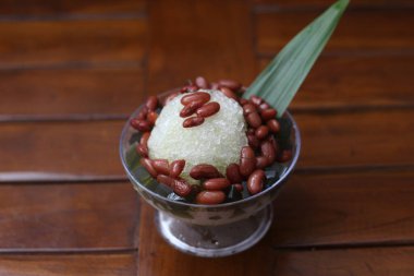 Es Kacang Merah or a cold drink made from red beans boiled with brown sugar served with coconut milk, shaved ice and covered with sweetened condensed milk chocolate and syrup. Indonesian traditional food photo concept.