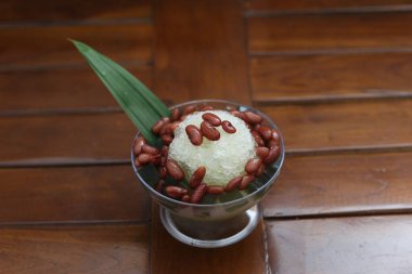 Es Kacang Merah or a cold drink made from red beans boiled with brown sugar served with coconut milk, shaved ice and covered with sweetened condensed milk chocolate and syrup. Indonesian traditional food photo concept.